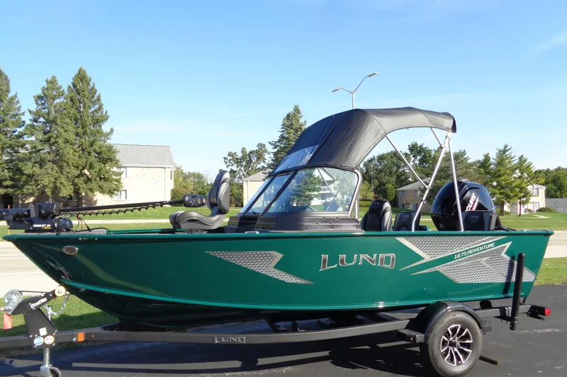 Slide: The Image of 2026 Lund 1675 Adventure Sport boat on trailer, green exterior, parked outdoors. - 19
