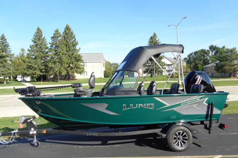 Slide: The Image of 2026 Lund 1675 Adventure Sport boat on trailer, green exterior, parked outdoors. - 2