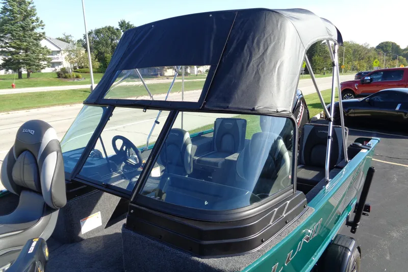 Slide: The Image of 2026 Lund 1675 Adventure Sport boat with canopy and seating, parked outdoors. - 20
