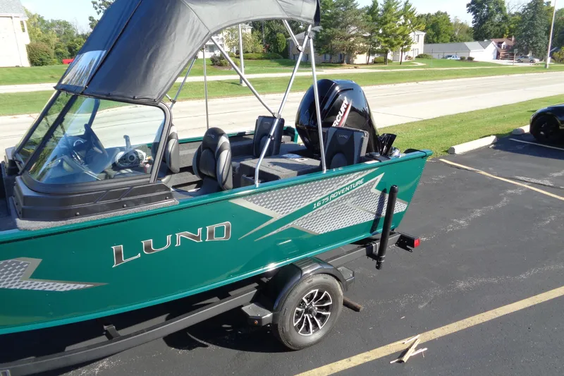 Slide: The Image of 2026 Lund 1675 Adventure Sport boat with canopy on a trailer in a parking lot. - 3