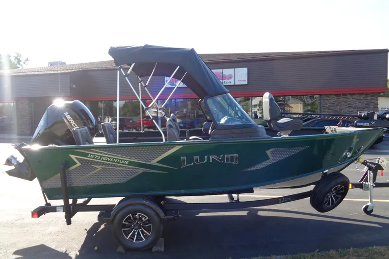 Slide: The Image of 2026 Lund 1675 Adventure Sport boat on trailer, parked outside a building. - 9