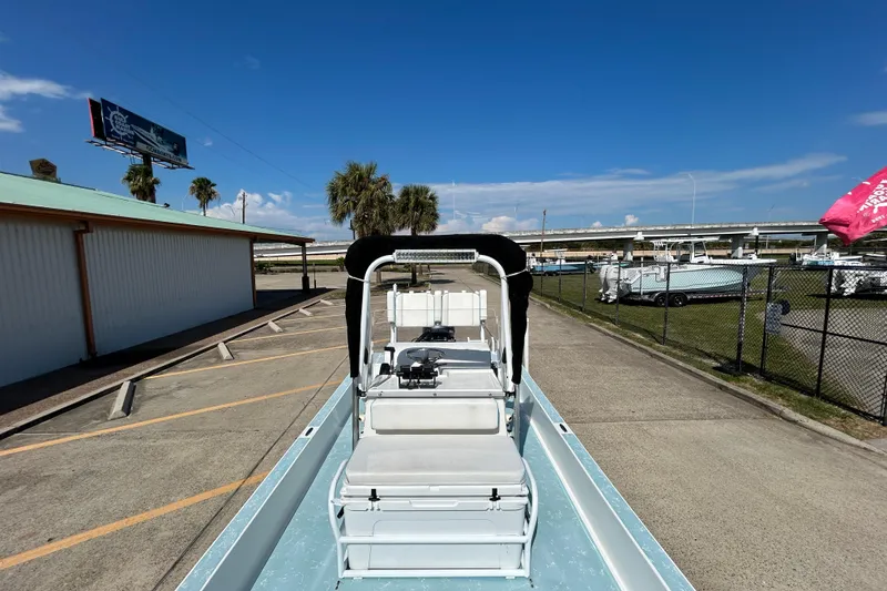 Slide: The Image of 2016 Shallow Sport 21 Sport boat parked outdoors under clear blue sky. - 15