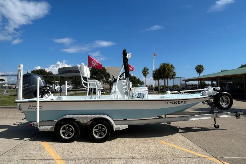 Slide: The Image of 2016 Shallow Sport 21 Sport boat on trailer, parked outdoors under clear blue sky. - 5
