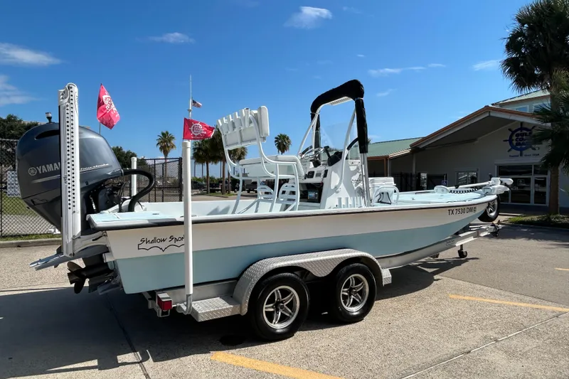 Slide: The Image of 2016 Shallow Sport 21 Sport boat on trailer, featuring Yamaha engine, parked outdoors. - 6