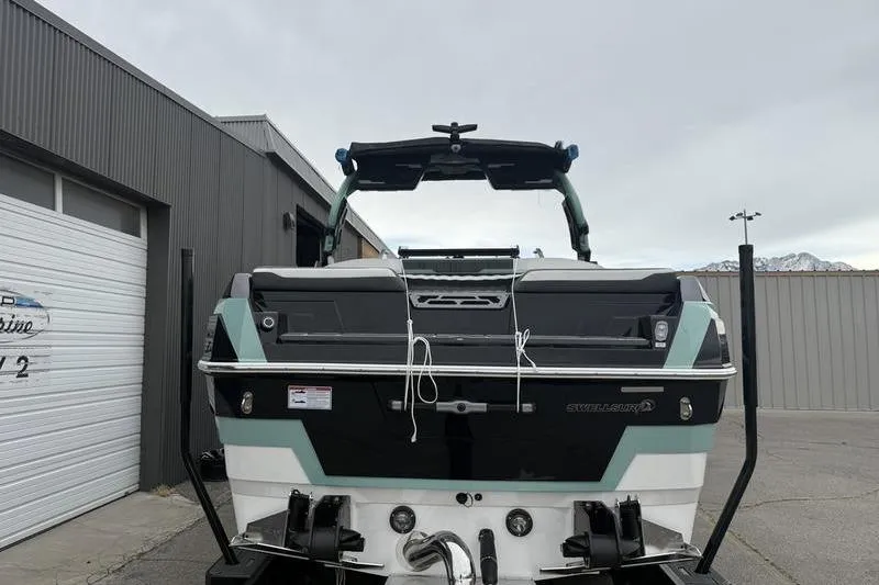 Slide: The Image of 2025 Supra SL 575 boat, rear view, parked outside a warehouse. - 2