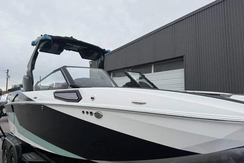 Slide: The Image of 2025 Supra SL 575 boat with sleek black and white design, parked outdoors. - 3