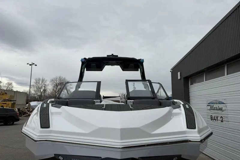 Slide: The Image of 2025 Supra SL 575 boat front view, parked outdoors near a marina building. - 4