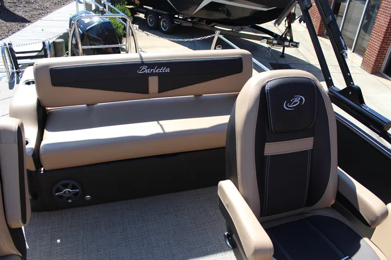 Slide: The Image of 2025 Barletta C24UC boat interior with tan and black seating, docked near a trailer. - 8