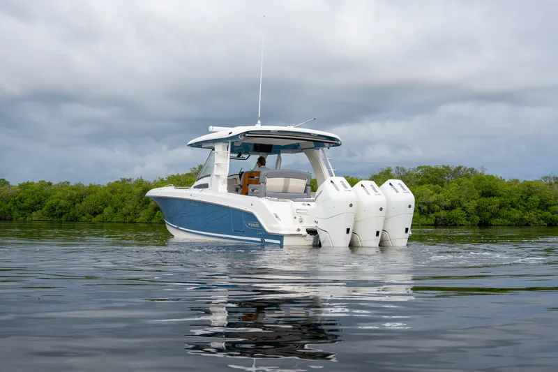 Slide: The Image of A 2026 Boston Whaler 350 Realm on calm water, surrounded by green vegetation. - 31