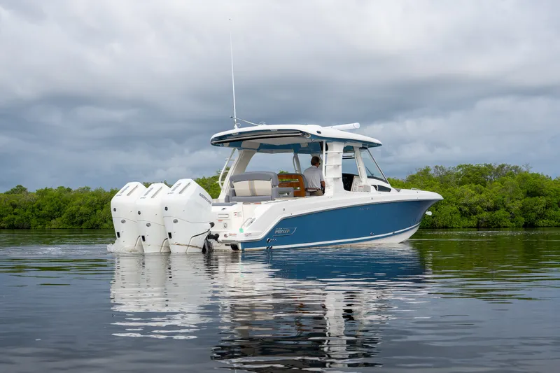 Slide: The Image of A 2026 Boston Whaler 350 Realm on calm water, featuring three outboard engines. - 30