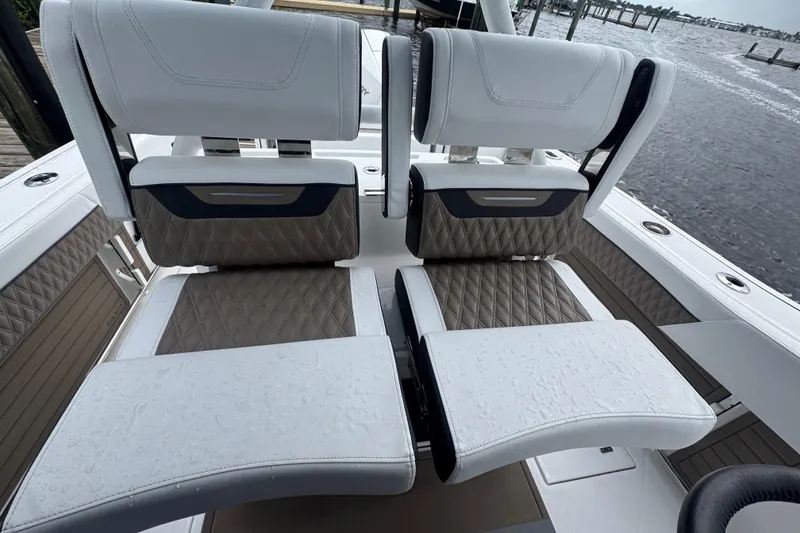 Slide: The Image of 2025 Blackfin 272CC boat seats with diamond-pattern upholstery, wet from rain, dockside view. - 11