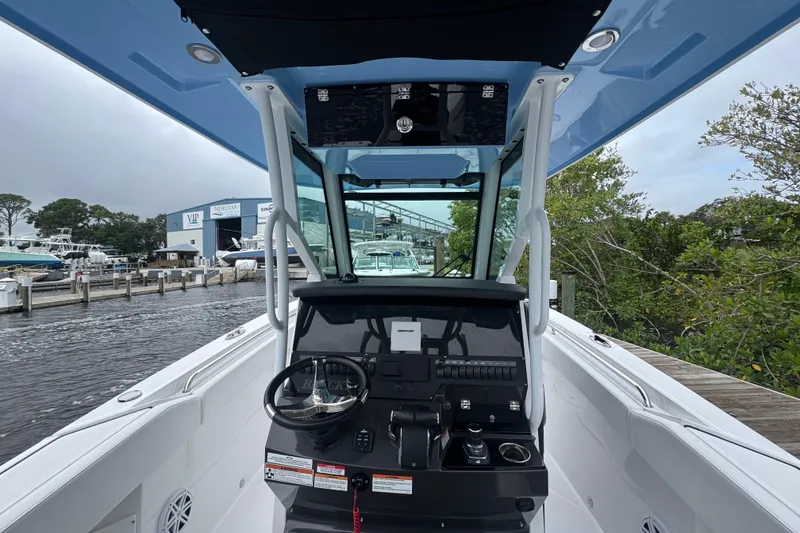 Slide: The Image of 2025 Blackfin 272CC boat cockpit with steering wheel, docked near marina. - 12