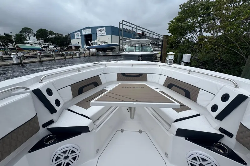 Slide: The Image of 2025 Blackfin 272CC boat interior with seating and table at a marina. - 5