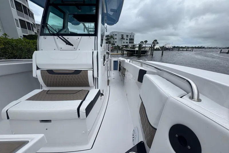 Slide: The Image of 2025 Blackfin 272CC boat interior with seating, docked by waterfront buildings. - 7