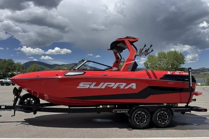 The Image of Red 2025 Supra SL 575 boat on trailer under cloudy sky. - 0
