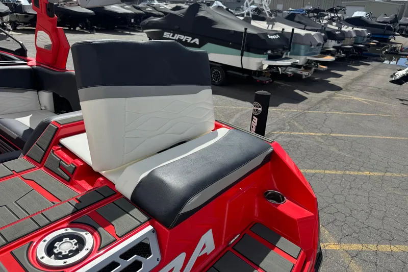 Slide: The Image of Red and black 2025 Supra SL 575 boat seat in a marina setting. - 13