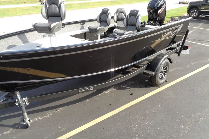 Slide: The Image of 2026 Lund 1800 Explorer Tiller boat on trailer, black exterior, parked outdoors. - 2