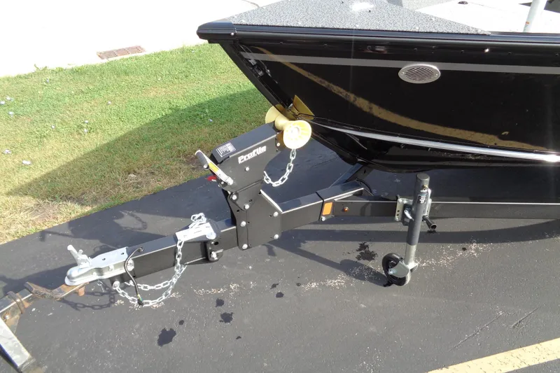 Slide: The Image of 2026 Lund 1800 Explorer Tiller boat trailer hitch on pavement, close-up view. - 3