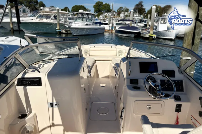 Slide: The Image of 2018 Grady-White Freedom 215 boat interior at marina, showcasing helm and seating area. - 9