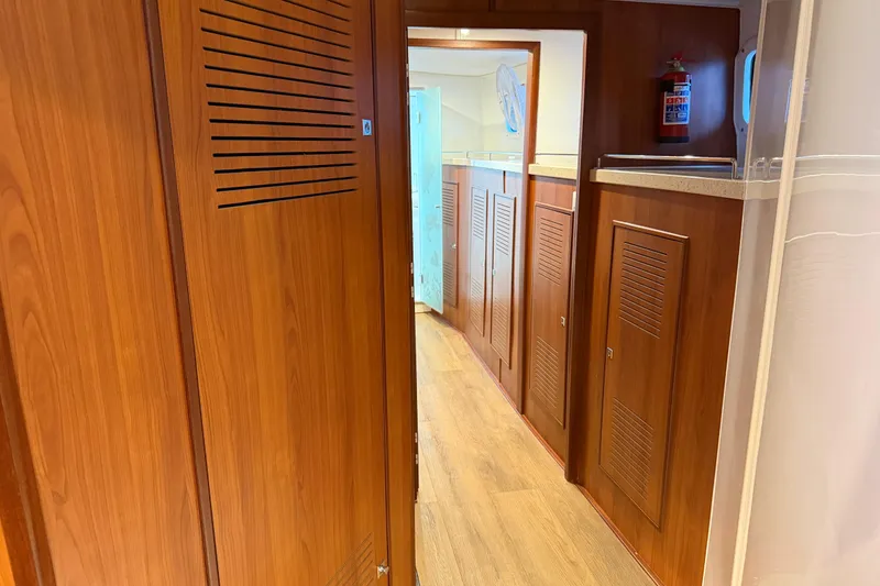 Slide: The Image of Interior hallway of 2023 Royal Cape Catamarans Majestic 530, featuring wooden cabinetry and flooring. - 102