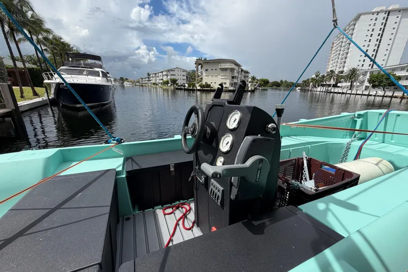 Slide: The Image of 2023 Royal Cape Catamarans Majestic 530 cockpit with steering wheel, docked near waterfront buildings. - 12