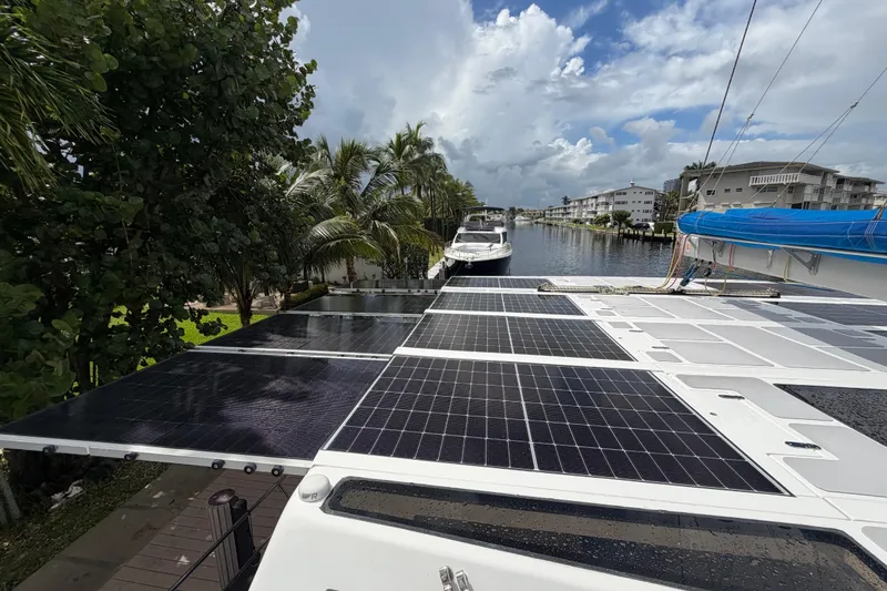 Slide: The Image of 2023 Royal Cape Catamarans Majestic 530 with solar panels, docked near palm trees and waterway. - 24