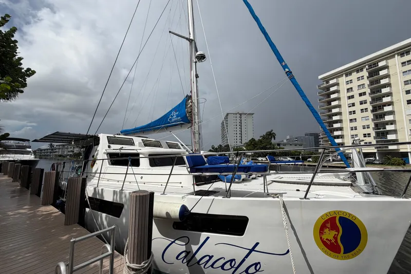 Slide: The Image of 2023 Royal Cape Catamarans Majestic 530 docked near modern buildings under cloudy sky. - 8