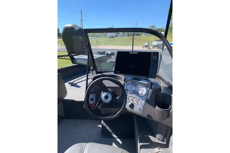 Slide: The Image of 2023 Bass Tracker Pro Guide V-16 WT boat dashboard with steering wheel and navigation display. - 5