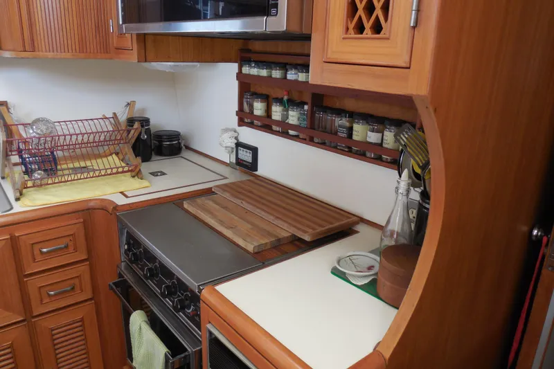 Slide: The Image of 1987 Hi-Star Sundeck yacht kitchen with wooden cabinetry, stove, spice rack, and dish rack. - 14
