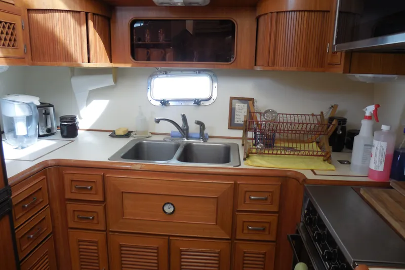 Slide: The Image of 1987 Hi-Star Sundeck yacht kitchen with wooden cabinets, sink, and appliances. - 15