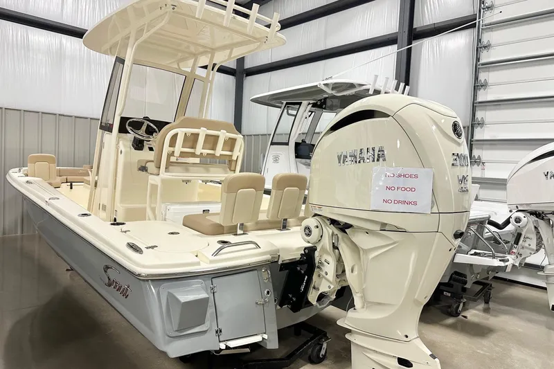 The Image of 2026 Scout 231 XSB boat with Yamaha engine in showroom, featuring beige seating and helm. - 3