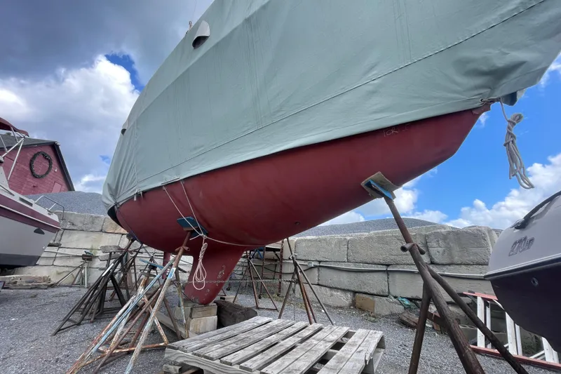 Slide: The Image of 1989 Sabre 30 MKIII sailboat on stands, covered, with a red hull and cloudy sky. - 25