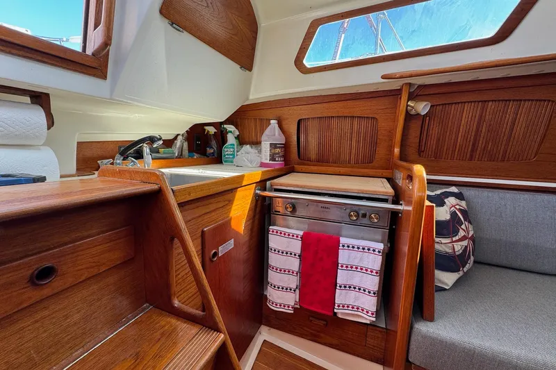 Slide: The Image of Cozy 1989 Sabre 30 MKIII yacht interior with wooden cabinetry, compact kitchen, and seating area. - 32