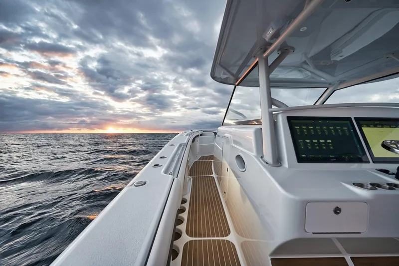 Slide: The Image of 2022 Yellowfin 54 Offshore boat at sea during sunset, featuring modern navigation equipment. - 10