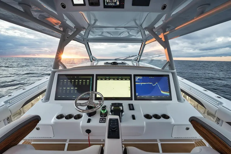 Slide: The Image of 2022 Yellowfin 54 Offshore boat cockpit with advanced navigation screens at sunset. - 13