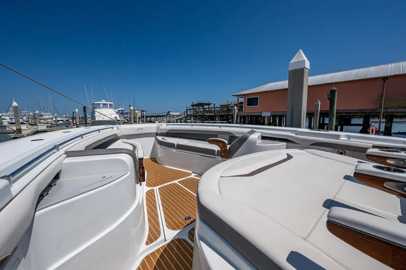 Slide: The Image of 2022 Yellowfin 54 Offshore boat interior with luxurious seating and wooden deck at marina. - 20