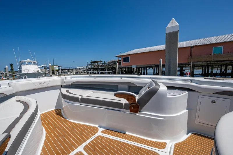 Slide: The Image of 2022 Yellowfin 54 Offshore boat interior with sleek seating and wooden deck, docked at marina. - 24