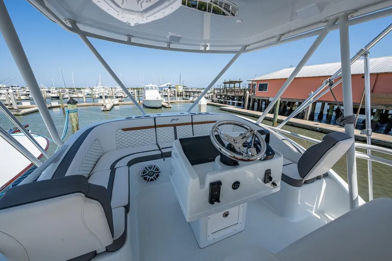 Slide: The Image of 2022 Yellowfin 54 Offshore boat helm with marina view, featuring modern seating and steering. - 72
