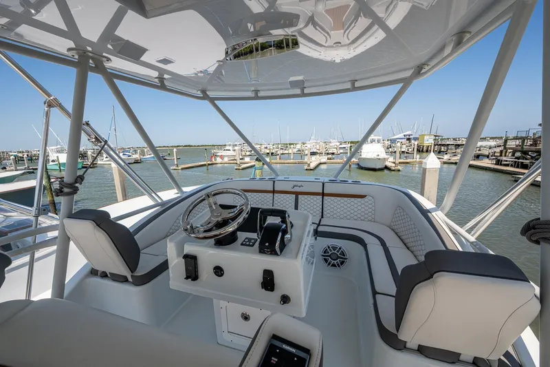 Slide: The Image of 2022 Yellowfin 54 Offshore boat helm with marina view, featuring modern steering and seating. - 79
