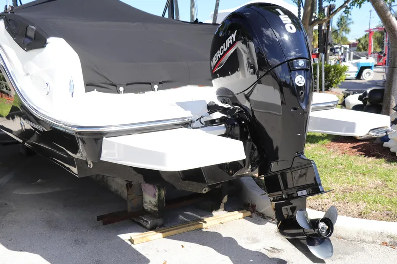 Slide: The Image of 2022 Bayliner DX 2200 boat with Mercury 150 outboard engine, parked outdoors. - 2