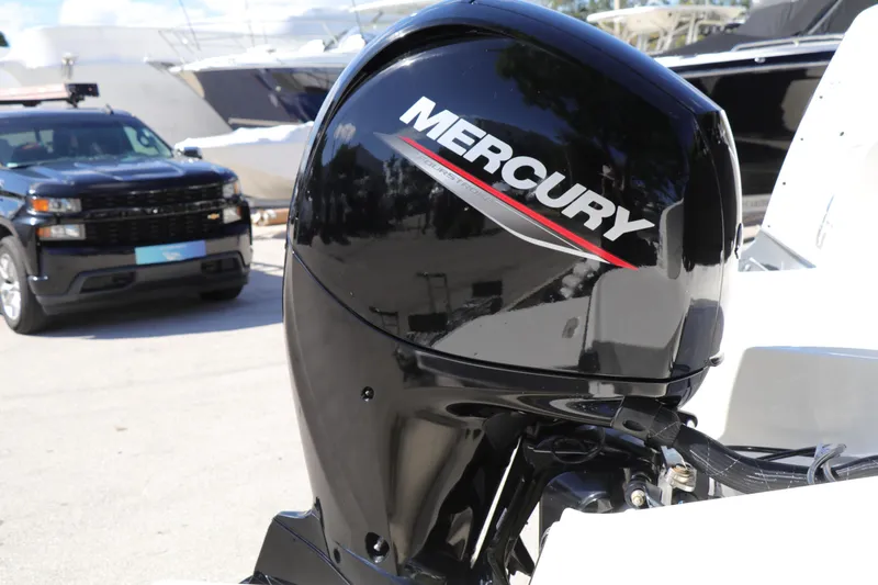 Slide: The Image of Mercury outboard motor on 2022 Bayliner DX 2200 boat, parked near vehicles. - 3