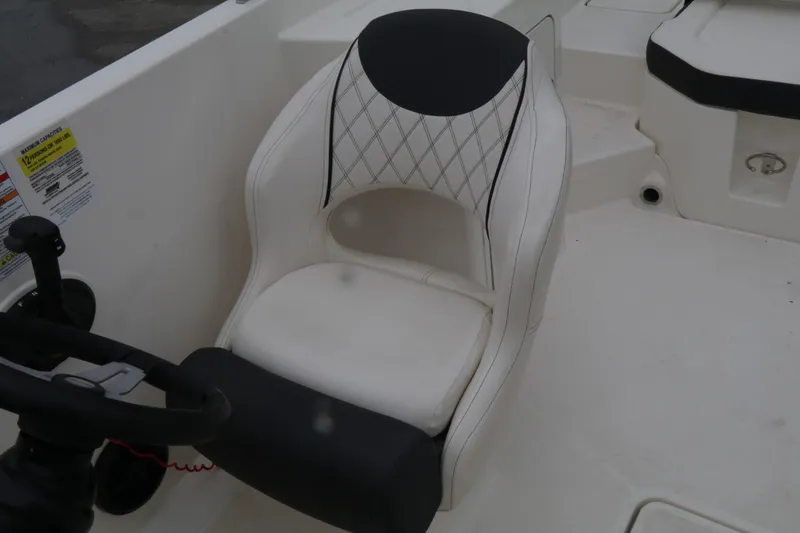 Slide: The Image of 2022 Bayliner DX 2200 boat seat with steering wheel, featuring white and black upholstery. - 8
