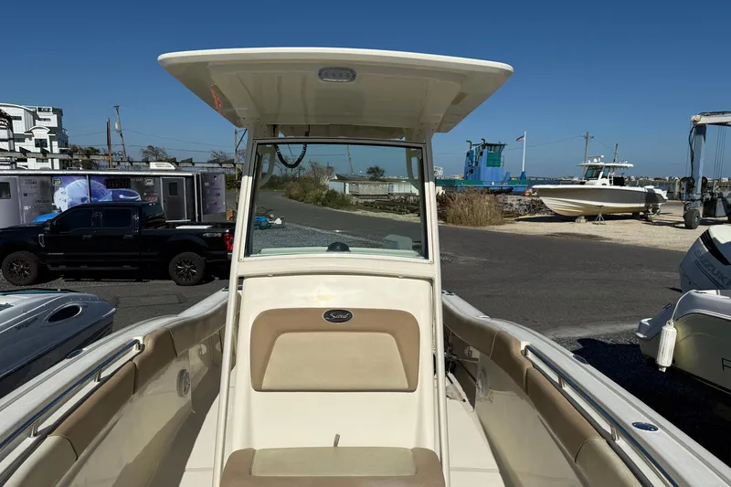 Slide: The Image of 2012 Scout 240 Bay Scout boat with T-top, docked near other boats and vehicles. - 11