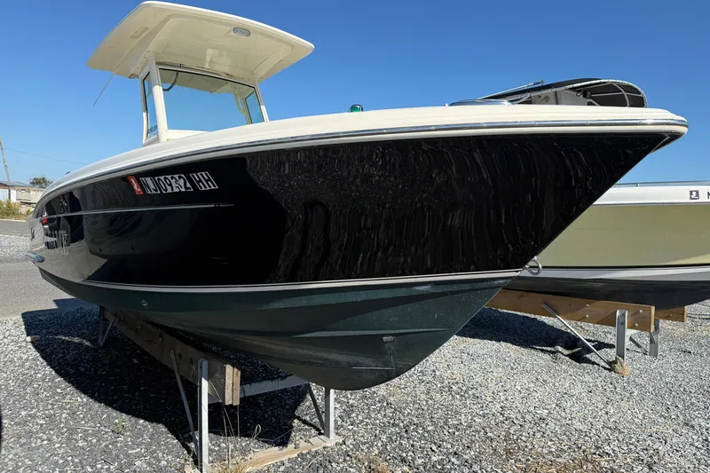 Slide: The Image of 2012 Scout 240 Bay Scout boat on gravel, side view under clear blue sky. - 3