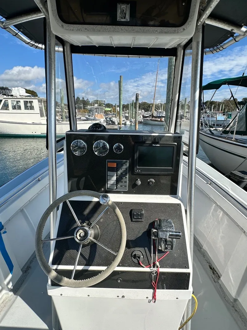 Slide: The Image of 1988 SeaCraft 23 Center Console boat dashboard with steering wheel and navigation instruments. - 11