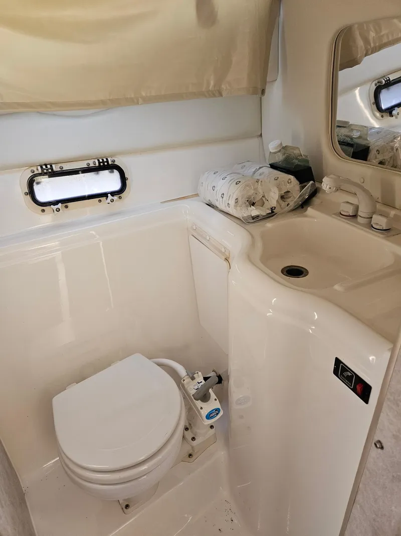 Slide: The Image of 1997 Bayliner 26 Cierra boat bathroom with toilet, sink, and window. - 3
