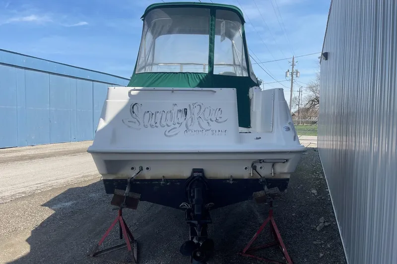 Slide: The Image of 1997 Bayliner 2655 Ciera boat with green canopy, parked on stands near a building. - 6