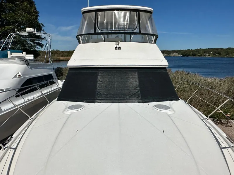 Slide: The Image of 2004 Silverton 38 Convertible yacht docked by a serene lake under clear blue skies. - 16