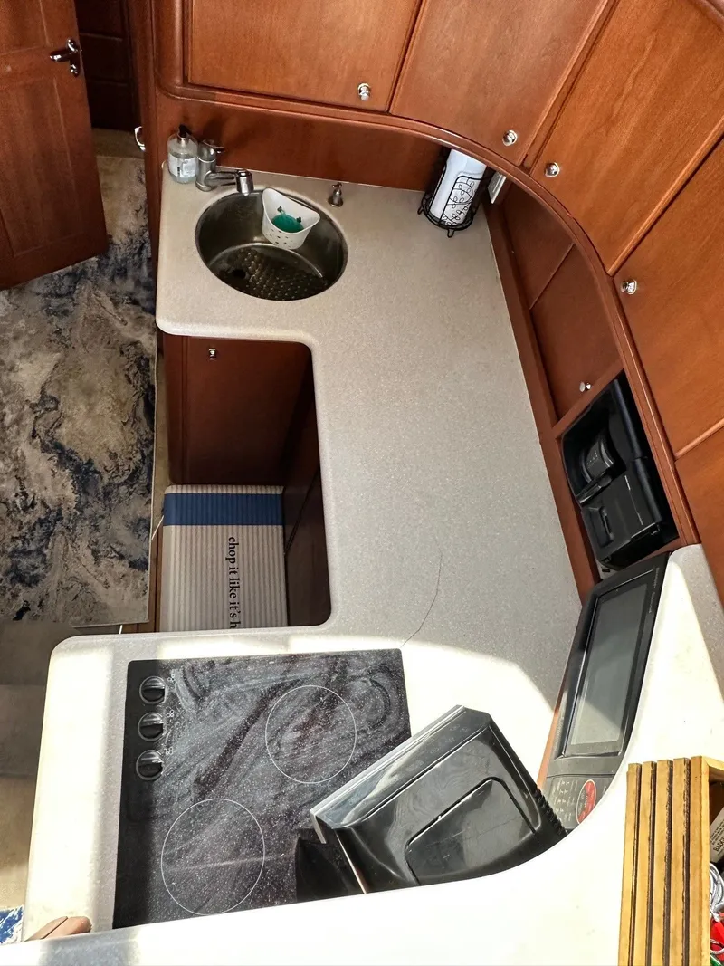 Slide: The Image of 2004 Silverton 38 Convertible yacht kitchen with sink, stove, and wooden cabinetry. - 40