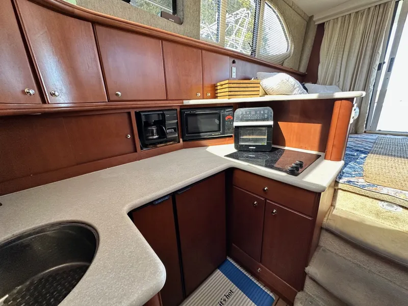 Slide: The Image of 2004 Silverton 38 Convertible yacht kitchen with wood cabinets, stove, microwave, and sink. - 43